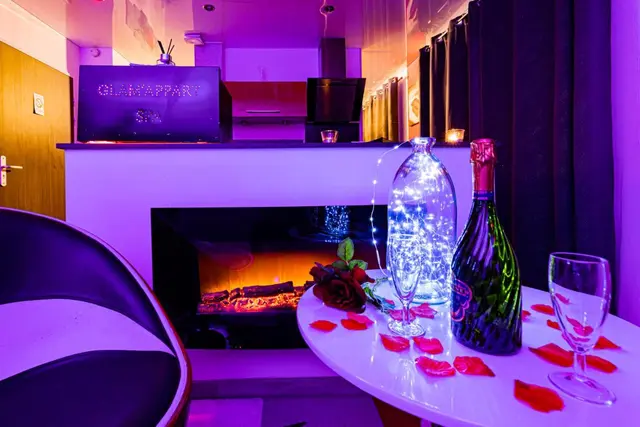 Champagne et pétales de rose devant la cheminée